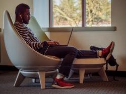 student sitting in a chair with his laptop