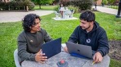 two students with laptops sitting and chatting