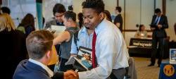 Image of a student shaking hands with a prospective employer at a campus career fair.